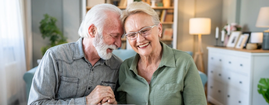 Life Assure Senior Woman Sitting In Chair And Laughing With Caregiver Nurse Hero